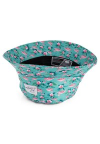 Floral bucket hat in teal, featuring pink flamingos and flowers. Made of soft fabric with a rippled edge and black lining.