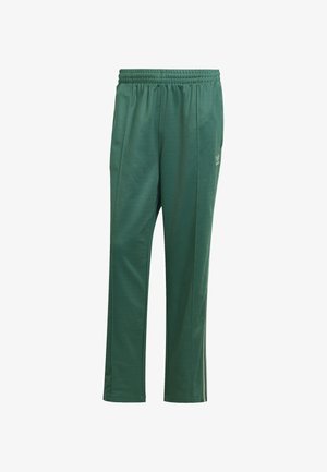 Zelené športové nohavice vyrobené z hladkej tkaniny, s elastickým pásom, bočnými švami a malým logom na ľavom stehne.