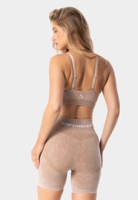 Beidzīga sporta krūšturis un augsto jostasvadu šorti komplekts. Iezīmes teksturēts audums, regulējamas siksnas un kontrastējošs balts logotips uz jostas.