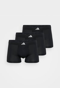 Boxer shorts pretos feitos de tecido liso, apresentando um design sólido e uma cintura elástica com três riscas diagonais brancas na parte da frente.