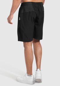 Svarta träningsshorts med en texturerad grå midja, med en åtsittande design och mesh sidofickor. Bärs med vita sneakers.