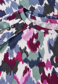 T-shirt met korte mouwen met een multikleurig abstract patroon in paars, groen en marineblauw op een witte stof, met een ronde hals en twee knoopaccenten.