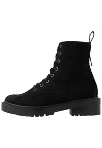 Botas de tobillo de ante negro con cordones, superficie texturizada, punta redonda y suela gruesa con ranuras de tracción, además de un tirador en la parte trasera.