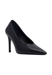 Zapato de tacón alto negro de cuero con punta afilada y un esbelto tacón de aguja sobre un fondo blanco.