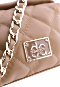 Bolso acolchado beige con correa de cadena dorada y placa con logotipo. Material de cuero suave con detalles de costura en contraste y textura lisa.