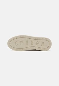 Sole of a sneaker in light beige with a textured rubber surface, featuring small bicycle motifs and raised letters "CPNHGN."