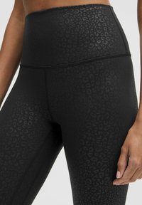 Hochtaillierte schwarze Leggings mit matter Oberfläche, versehen mit einem eingearbeiteten Leopardenmuster und Flachnaht-Nähten für zusätzlichen Komfort.