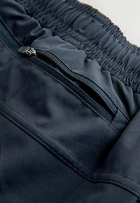 Granatowe szorty sportowe z elastycznym pasem i boczną kieszenią na zamek błyskawiczny. Gładka faktura materiału z widocznymi detalami szwów.