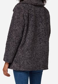 Oversized, textured dark gray coat with a short collar, featuring a soft, fluffy material and wide sleeves. No visible closures or pockets.