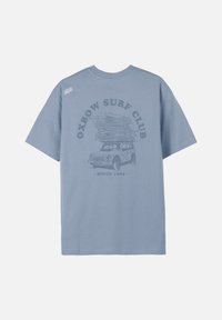 T-shirt bleu clair en coton avec une coupe décontractée, présentant un graphisme d'une voiture vintage transportant des planches de surf et le texte "Oxbow Surf Club" en gris.