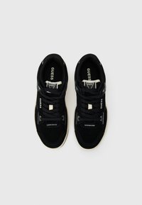 Black sneakers featuring a suede and fabric upper, lace closure, and rubber sole. Accents include contrasting white stitching and branding.