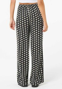 Pantaloni neri a gamba ampia con un motivo floreale bianco, vita elastica e tessuto morbido. Adatti per un abbigliamento casual.