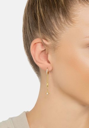 Gold hoop earrings with a delicate chain, featuring a small star detail and crystal accents, hanging just below the earlobe.