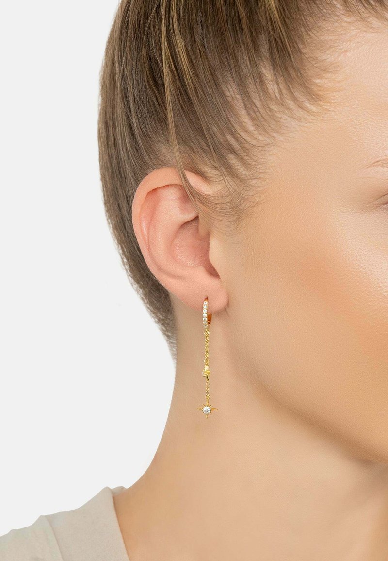 Gold hoop earrings with a delicate chain, featuring a small star detail and crystal accents, hanging just below the earlobe.