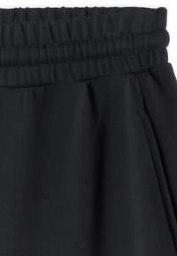 Pantalon de survêtement noir avec taille élastique, poche latérale et texture en tissu tricoté doux.
