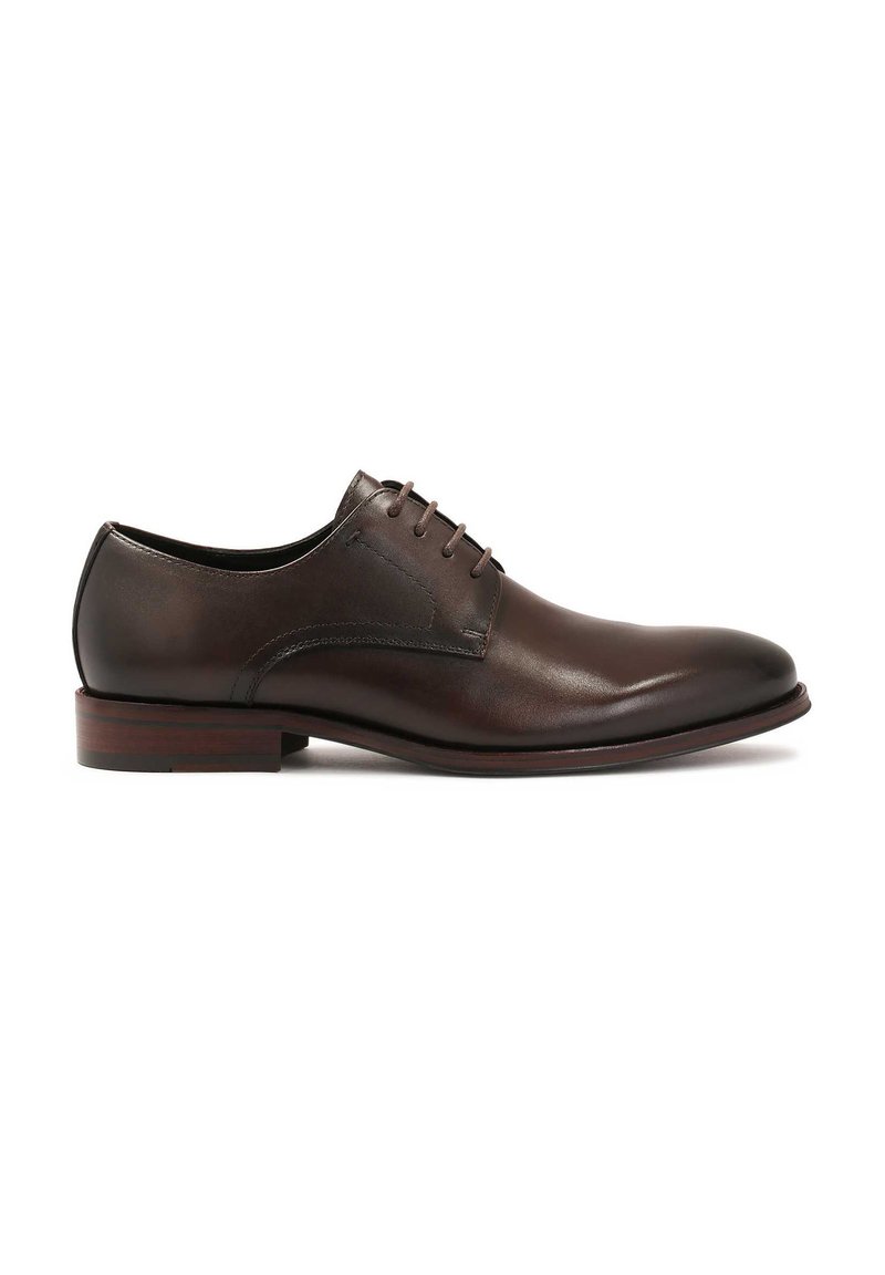 Scarpa da uomo in pelle marrone con texture liscia, punta rotonda e quattro paia di occhielli per i lacci. Presenta un tacco basso impilato e un design minimalista.