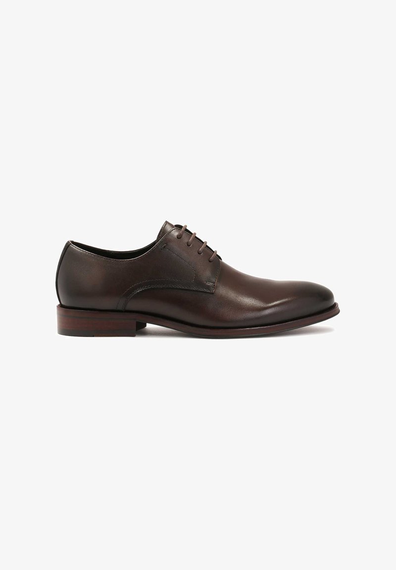 Scarpa da uomo in pelle marrone con texture liscia, punta rotonda e quattro paia di occhielli per i lacci. Presenta un tacco basso impilato e un design minimalista.