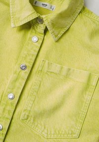 Camicia in denim verde lime con colletto a punta, bottoni a pressione argentati e tasca sul petto. Il tessuto ha una finitura testurizzata.