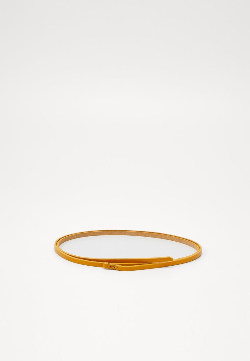 Ceinture fine en cuir jaune moutarde enroulée à plat sur une surface blanche avec une petite boucle rectangulaire.