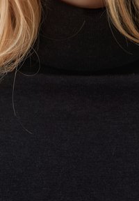 Pull à col roulé noir ; tissu tricoté avec une texture douce ; vue en gros plan mettant en évidence la finition lisse et le design à col haut.