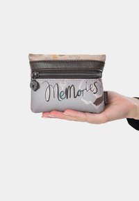 Monedero de cuero gris con cierre, que presenta la palabra "Recuerdos" y un patrón texturizado en colores tenues. Diseño compacto y práctico.
