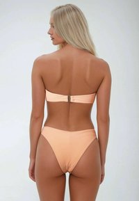 Perzik bandeau bikini met een gestructureerde afwerking en een subtiele glans. Gemaakt met een centrale sluiting en een hoog uitgesneden onderkant voor een slankere silhouet.