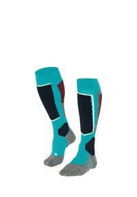 Chaussettes montantes avec une base turquoise, des panneaux texturés noirs et bordeaux, et des sections grises au niveau des pieds. Elles présentent des accents en zigzag le long des coutures.