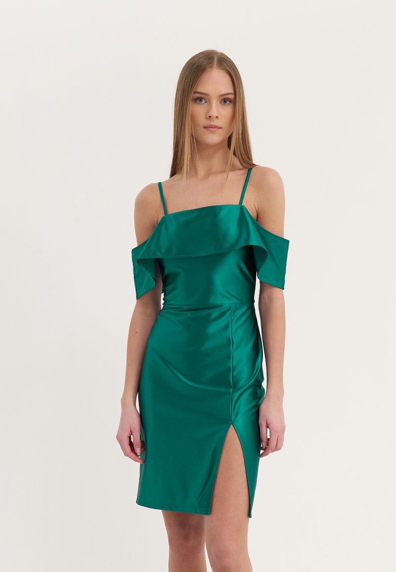 Robe en satin verte avec un design décolleté, détail de volants évasés et une fente sur le côté. Silhouette ajustée et élégante mettant en valeur une texture lisse.