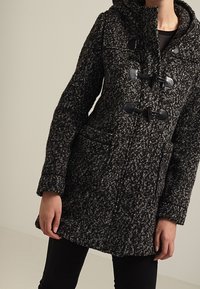 Płaszcz typu duffle wykonany z mieszanki wełny w kolorze czarnym i szarym, z teksturowanym wzorem, z zapięciem na toggle, kapturem oraz dwiema przednimi kieszeniami.