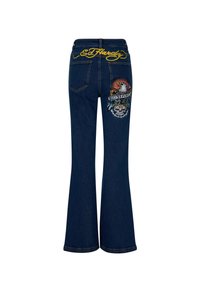 Jeans acampanados de color azul oscuro con diseños bordados de un tigre y un águila, con "Ed Hardy" bordado en amarillo en la cinturilla.