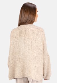 Beige oversized Strickpullover mit einem strukturierten, groben Muster. Verfügt über einen weiten Halsausschnitt und lange Ärmel, die unter die Hüfte fallen.
