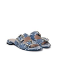 Blue denim slide sandals featuring two rhinestone-embellished buckles, frayed edges, and a flat sole. Soft texture and open-toe design.