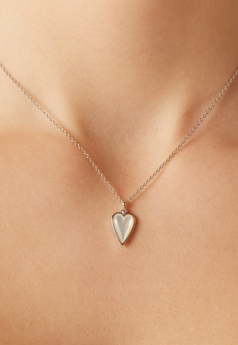 Zilveren ketting met een hartvormige hanger. De hanger heeft een glad, reflecterend oppervlak met een subtiele glans en een gestructureerde ketting.