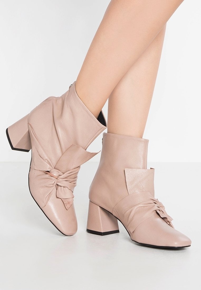 Beiga läderankelstövlar med en snodd detalj, fyrkantiga klackar och slät yta; har en dragkedjestängning på sidan.