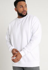 Witte sweater met een ronde hals, lange mouwen en geribbelde manchetten. Zachte stof met een gladde textuur en een relaxte pasvorm.