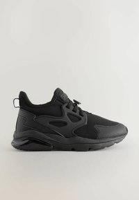 Chaussure de sport noire présentant un design en matériaux mixtes composé de tissu et de cuir synthétique, avec une semelle texturée et un système de laçage élastique.