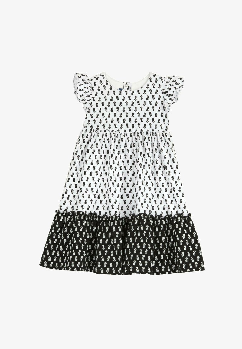 Robe blanche avec imprimé floral noir, manches courtes en volant, et ourlet à volants noirs en plusieurs niveaux. Dispose d'une fermeture à boutons au dos.