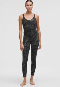 Černá sportovní podprsenka a legíny s nenápadným květinovým vzorem, elastický materiál, přiléhavý střih a široké ramínka pro oporu.