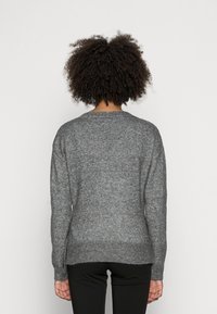 Grå stickad tröja med avslappnad passform, rund halsringning och ribbat avslut. Tillverkad av mjukt garn med en texturerad yta, lämplig för lager-på-lager.