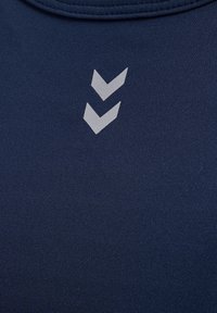 Marinblå sporttopp av slät tyg med rund halsringning och två silvriga markeringar i form av chevrons framtill.