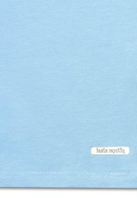 Lys blå bomulds t-shirt med en glat tekstur, der har et lille sølvmærke, der står "bazix republiq" nær kanten.