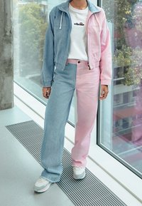 Světlá modrá a růžová džínová bunda, zkrácená. Bílé tričko s logem. Růžové a modré široké džíny s rozdělenou barvou. Bílé tenisky s pastelovými akcenty.