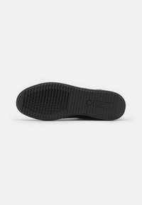 Semelle de chaussure en caoutchouc noir avec motifs antidérapants texturés et logo Geox rectangulaire, affichée à plat sur fond blanc.