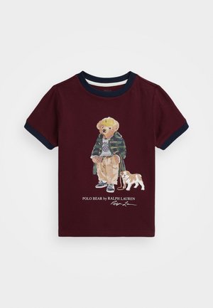 Bordeaux-kleurig T-shirt met korte mouwen en marineblauwe accenten, met een afbeelding van een beer in een groene jas en beige broek, vergezeld door een kleine hond.