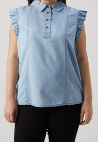 Top in denim azzurro chiaro con colletto, maniche corte arricciate e patta dei bottoni con bottoni marroni. Texture liscia.