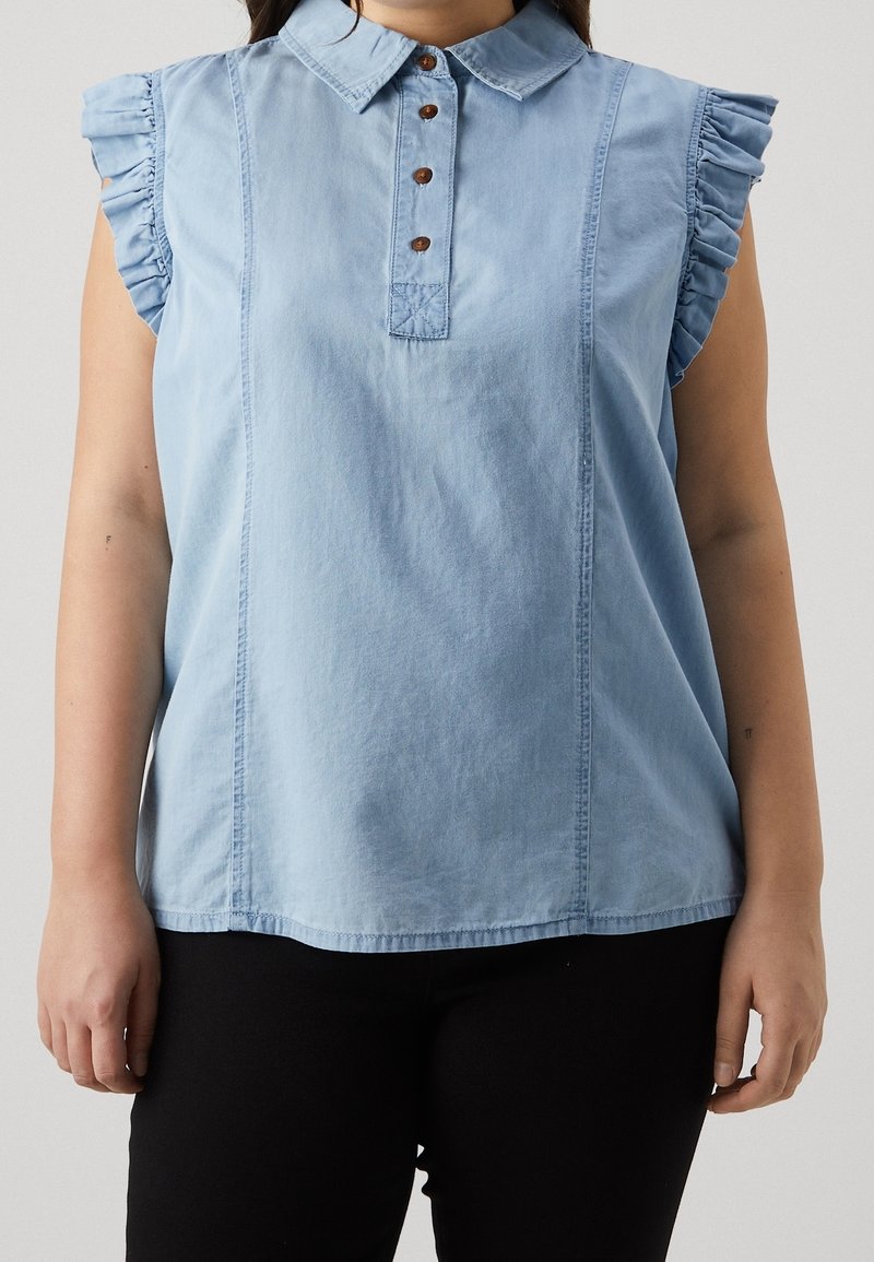 Top in denim azzurro chiaro con colletto, maniche corte arricciate e patta dei bottoni con bottoni marroni. Texture liscia.