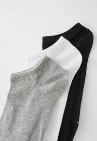 Drei Paar Knöchelsocken: eine graue, eine weiße und eine schwarze. Aus Baumwolle gefertigt, mit gerippten Bündchen und einer glatten Textur.