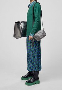 Grön metallic stickad tröja, mönstrad grön och blå maxi kjol, svarta platåstövlar med gröna sulor, silverväskor, stilren design och texturer.