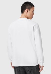 Weißes Langarmshirt mit rundem Halsausschnitt, lässiger Passform und gerippten Bündchen. Glatte Textur ohne sichtbare Muster oder Logo-Details.