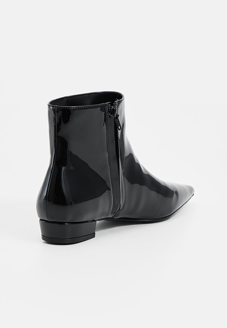 Czarne lakierowane botki za kostkę z wydłużonym noskiem, niskim obcasem klockowym oraz zamkiem błyskawicznym z tyłu. Gładka, błyszcząca tekstura z dopasowaną sylwetką.